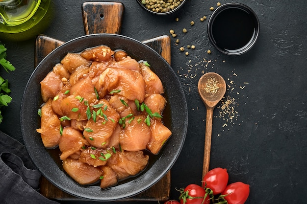 Carne de frango crua marinada em molho de soja teriyaki, cebola e pimenta em um prato preto