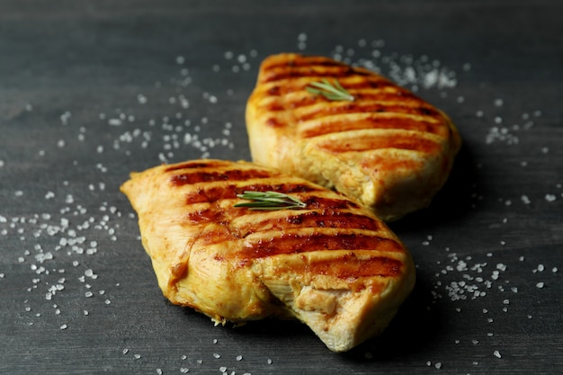 Carne de frango grelhado e sal em fundo escuro de madeira