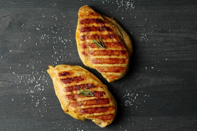 Carne de frango grelhado e sal em fundo escuro de madeira