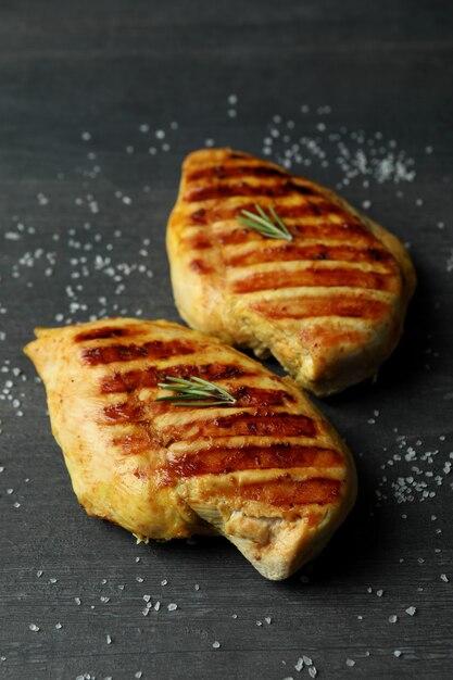 Carne de frango grelhado e sal em fundo escuro de madeira