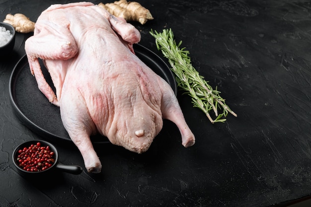 Carne de ganso inteira crua na mesa preta, com espaço de cópia.