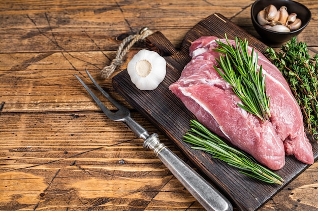 Carne de ombro de porco crua fresca com ingredientes e especiarias na placa de açougueiro de madeira. fundo de madeira. Vista do topo. Copie o espaço.