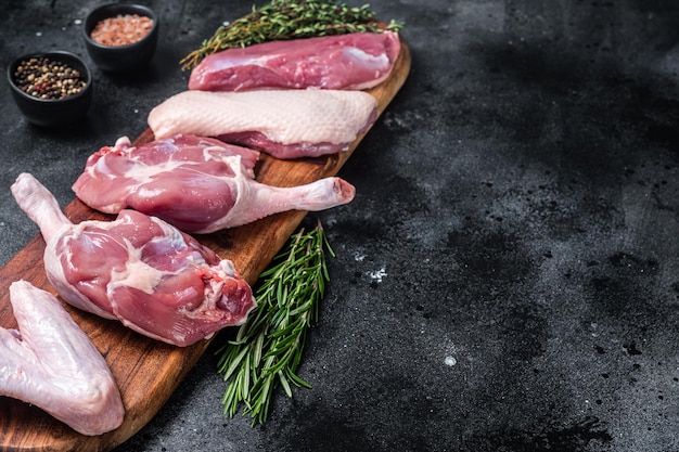 Carne de pato crua pronta para cozinhar asas de pernas de filé de peito Fundo preto Vista superior Espaço para cópia