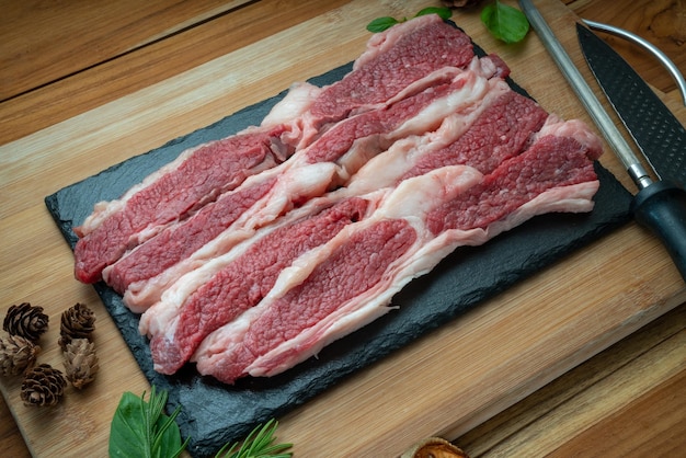 Carne de peito fatiada fresca na placa preta Carne de peito fatiada em fundo de madeira