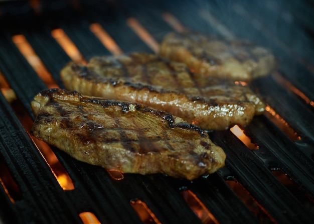 Foto carne de picanha grelhada cortada com fogo e fumaça com escuras