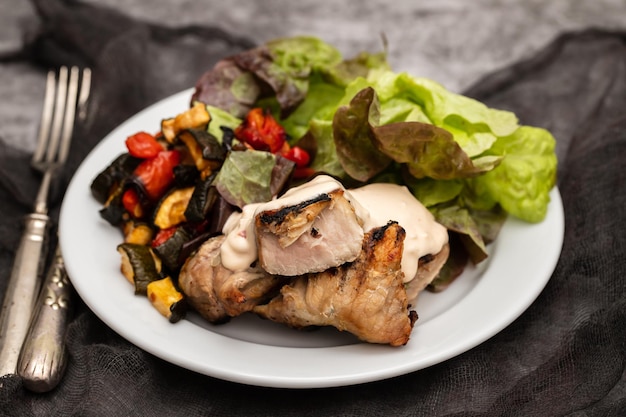 Carne de porco assada com legumes e salada fresca no prato