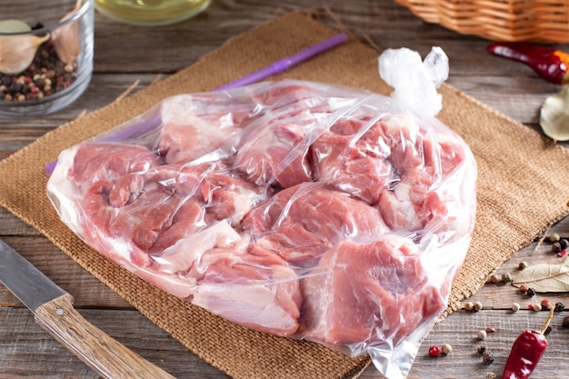 Carne de porco congelada em embalagem plástica sobre uma mesa de madeira. Alimentos congelados