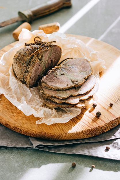 Foto carne de porco cozida com alho e especiarias em uma bandeja de madeira, fundo cinza