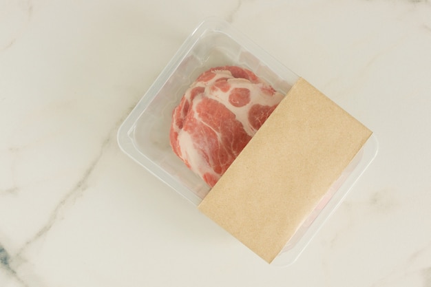 Carne de porco crua bife a vácuo Embalado em fundo de mármore, vista superior, maquete para designers.
