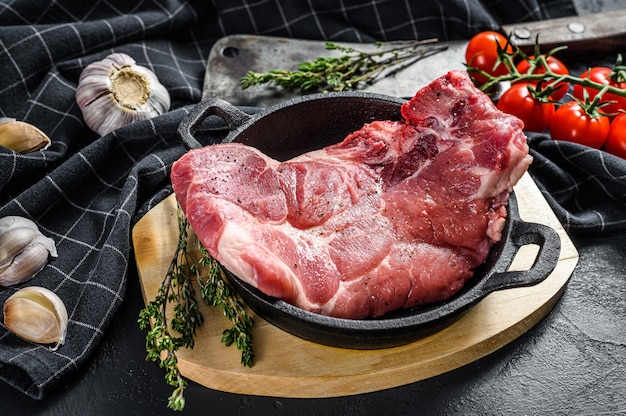 Carne de porco crua com osso, bife de mármore em uma frigideira.