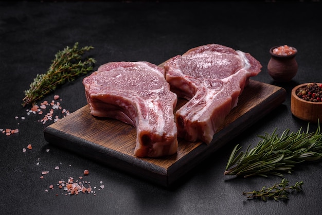 Carne de porco crua fresca nas costelas com especiarias e ervas numa tábua de corte de madeira