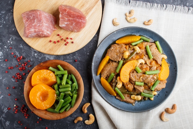 Carne de porco frita com pêssegos, caju e feijão verde. carne crua, pimenta vermelha, tecido de linho.