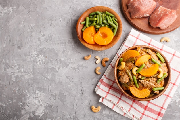 Carne de porco frita com pêssegos, caju e feijão verde no preto