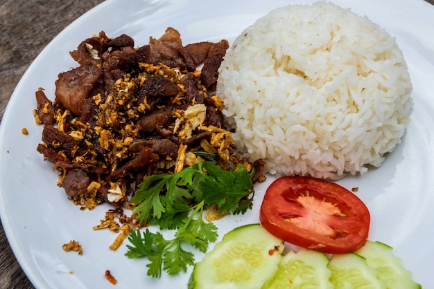 Carne de porco frito com alho, coentro, tomate fatiado, pepino fatiado, perto de arroz em p branco