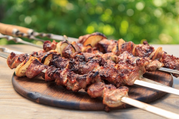 Foto carne de porco grelhada no espeto assado na grelha na tábua de madeira. churrasco, piquenique