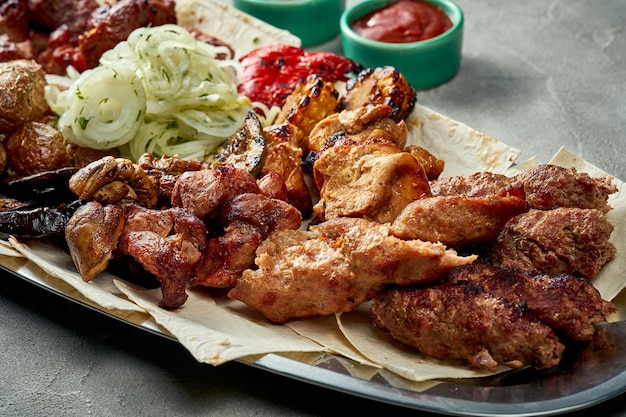 Carne de porco grelhada variada e kebab de frango em um prato com molho e pão pita Closeup