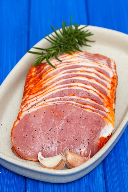 Foto carne de porco marinada em prato na superfície azul