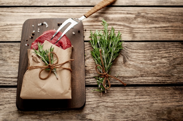 carne de um açougue embrulhada em papel. Um pedaço de carne na madeira com especiarias diferentes em estilo rústico