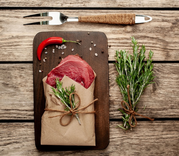 carne de um açougue embrulhada em papel. Um pedaço de carne na madeira com especiarias diferentes em estilo rústico