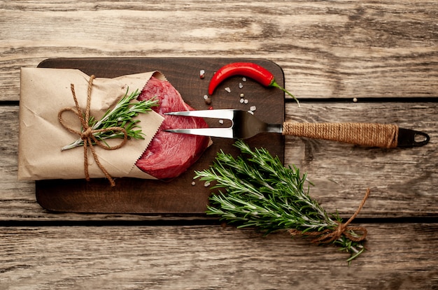 carne de um açougue embrulhada em papel. Um pedaço de carne na madeira com especiarias diferentes em estilo rústico