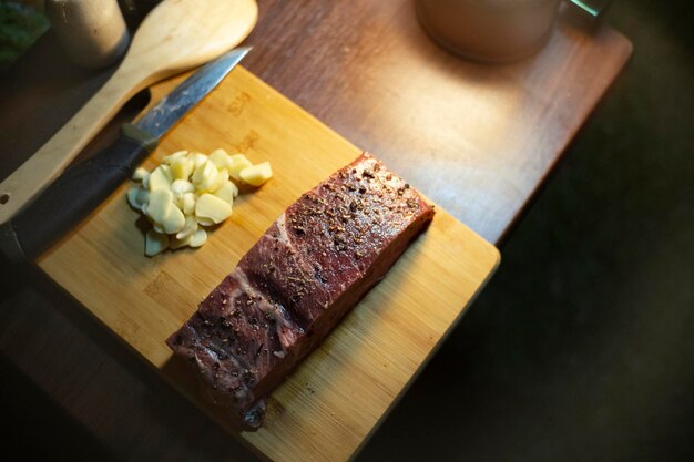 Foto carne de vaca de alta qualidade servida em uma tábua de cortar de madeira e temperada com especiarias para uma festa noturna