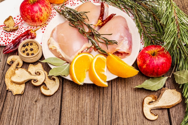 Carne desossada de frango cru com ervas e frutas no prato. Cozinhar no dia de ação de Graças