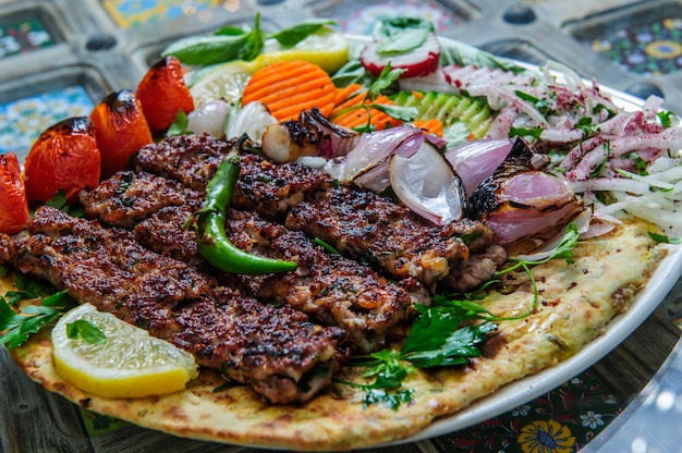 Carne diferente de churrasco saudável com legumes e molho. servido com um prato preto. close-up vista sobre um fundo claro. conceito de comida