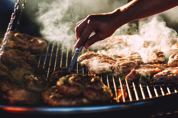 Carne e salsichas são fritas na grande grelha no café da rua.