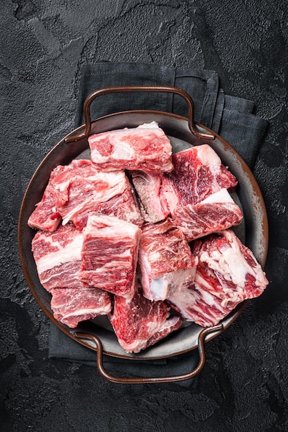 Carne em cubos crua e carne marmorizada de cordeiro na bandeja de aço da cozinha Fundo preto Vista superior