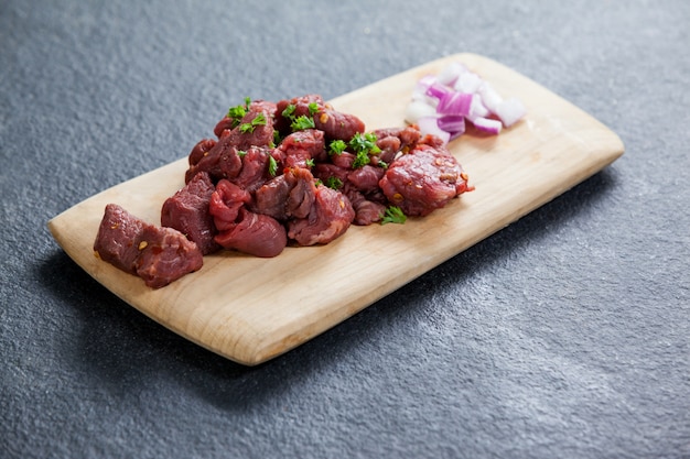 Carne em cubos e cebolas na placa de madeira