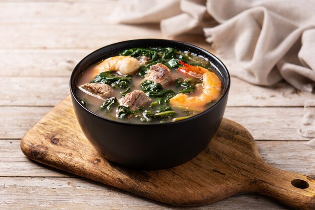 Carne, ensopado de quiabo e sopa de espinafre em uma tigela na mesa de madeira