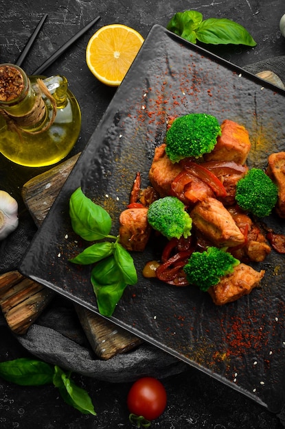 Carne estufada em molho de vinho com brócolis e legumes na placa de pedra preta vista superior