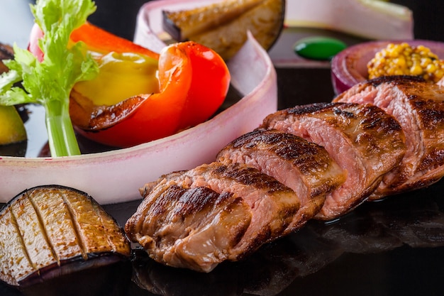 Foto carne fatiada com ervas frescas, vegetais e especiarias na vista superior do fundo preto