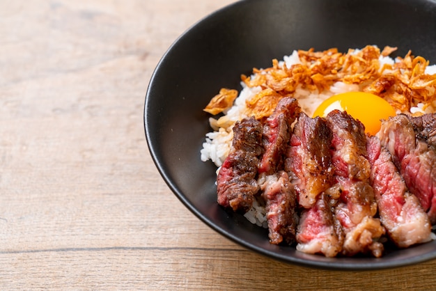 carne fatiada em tigela de arroz coberto com ovo