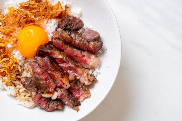 Carne fatiada na tigela de arroz coberto com ovo