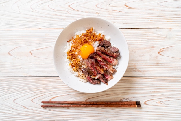 carne fatiada na tigela de arroz coberto com ovo