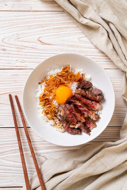 carne fatiada na tigela de arroz coberto com ovo