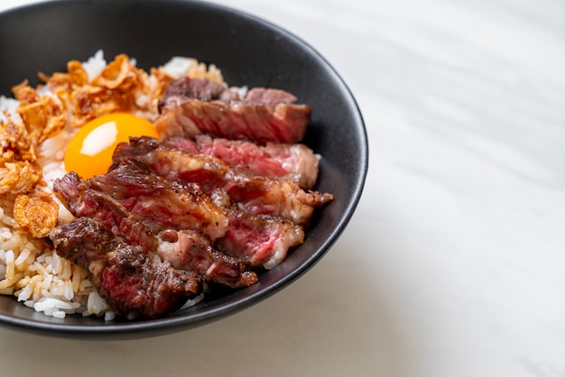 carne fatiada na tigela de arroz coberto com ovo