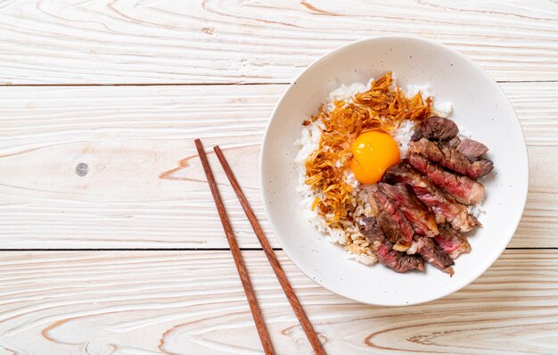 carne fatiada na tigela de arroz coberto com ovo