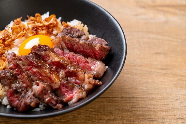 carne fatiada na tigela de arroz coberto com ovo