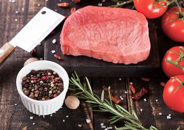 Carne de filete de res cruda fresca en tablero de cocina de madera con hacha y pimienta