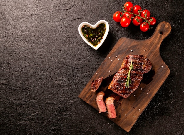 Carne fresca a la brasa. Filete de ternera a la parrilla medio raro sobre plancha de madera. Vista superior.