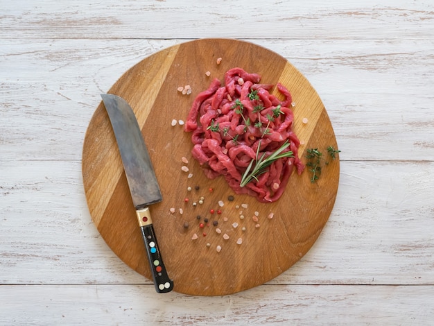 Carne fresca cortada en tiras finas sobre una tabla para cortar.