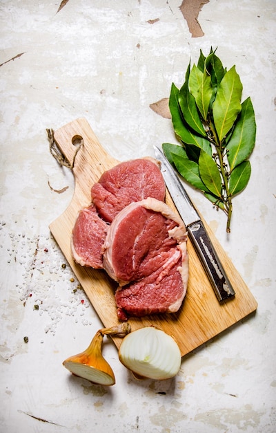 Carne fresca crua a bordo com especiarias em fundo rústico