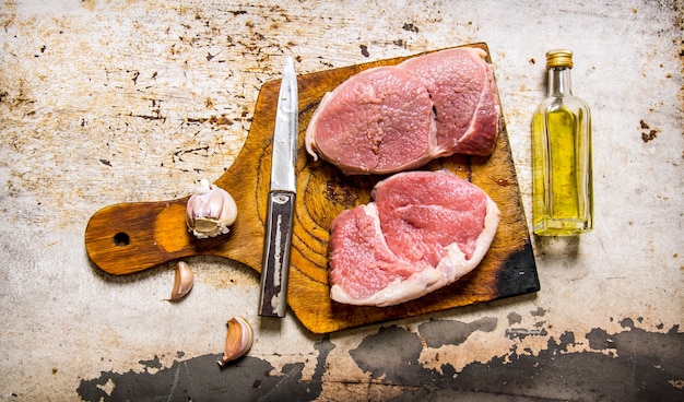 Carne fresca crua com alho e óleo em uma placa de madeira