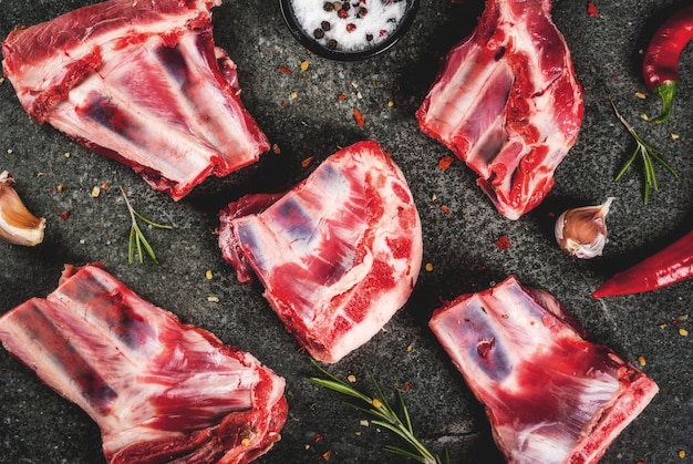 Carne fresca cruda, cordero crudo o costillas de ternera con pimiento picante, ajo y especias sobre fondo de piedra oscura