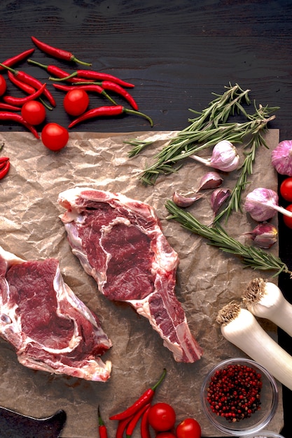 Carne fresca cruda con ingredientes para cocinar en la mesa oscura