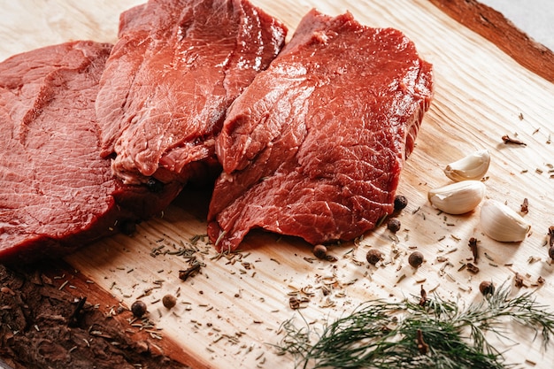 Carne fresca cruda en una tabla de madera con especias.