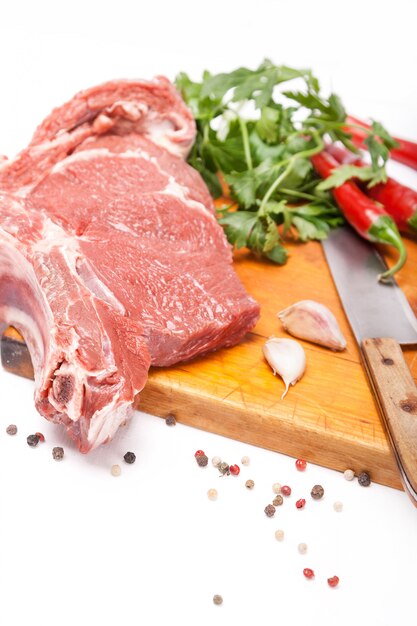 Carne fresca de res con hueso sobre especias de madera y cuchillo