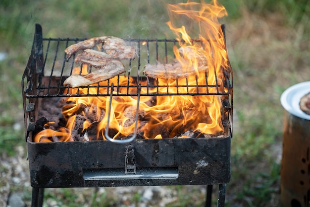 La carne se fríe en una parrilla en llamas en condiciones de campo.